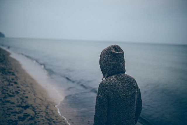 σχιζοειδής διαταραχή προσωπικότητας άνδρας με κουκούλα περπατάει στην παραλία